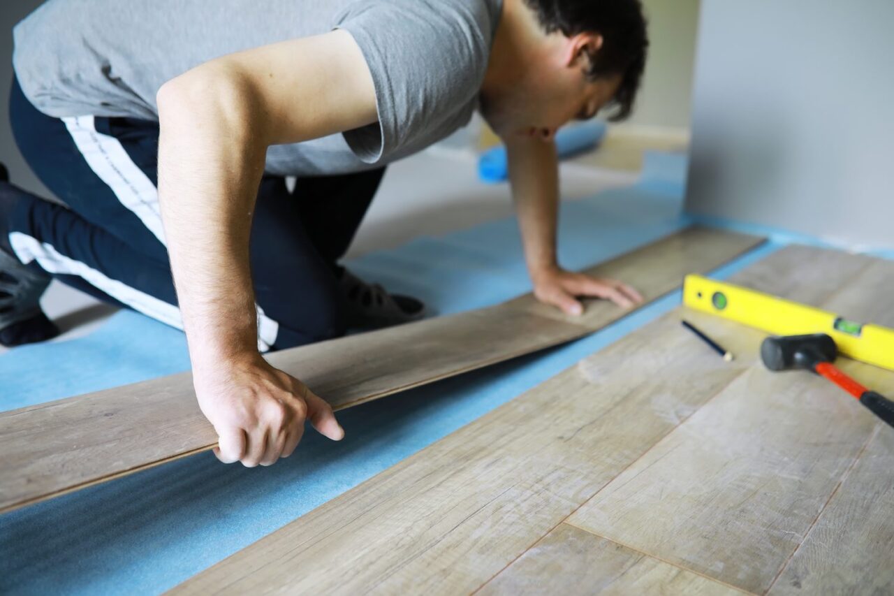 Pose de lames de parquet sur un ancien carrelage dans une pièce intérieure.